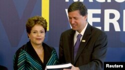 Brazilian President Dilma Rousseff receives the report from Pedro Dallari, a member of the truth commission, in Brasilia, Dec. 10, 2014.