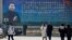 People walk in front of a poster showing a portrait of Chinese President Xi Jinping in Beijing, China, Feb. 26, 2018. 