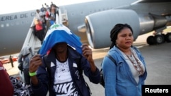 FILE - A Haitian man covers his face with a flag after disembarking from a Chilean Air Force plane upon his arrival at the International Airport of Port-au-Prince, Haiti, Nov. 7, 2018.