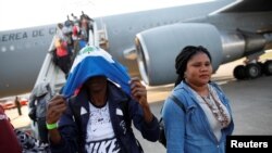 Seorang pria Haiti menutupi wajahnya setelah turun dari pesawat Angkatan Udara Chili setibanya di Bandara Internasional Port-au-Prince, Haiti, 7 November 2018. Enam orang, termasuk dua misionaris AS, tewas saat sebuah pesawat carteran jatuh di Haiti. (Foto: Reuters)