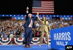 FILE - Minnesota Governor and Democratic vice presidential candidate Tim Walz (L) gestures alongside US Vice President and Democratic presidential candidate Kamala Harris at Desert Diamond Arena in Glendale, Arizona, on August 9, 2024. (Photo by Robyn Beck / AFP)