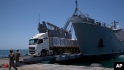 Un soldado del ejército estadounidense da instrucciones a un camión cargado con ayuda humanitaria que desembarca en el muelle flotante construido por Estados Unidos, antes de llegar a la playa, en la costa de la Franja de Gaza, el martes 25 de junio de 2024.