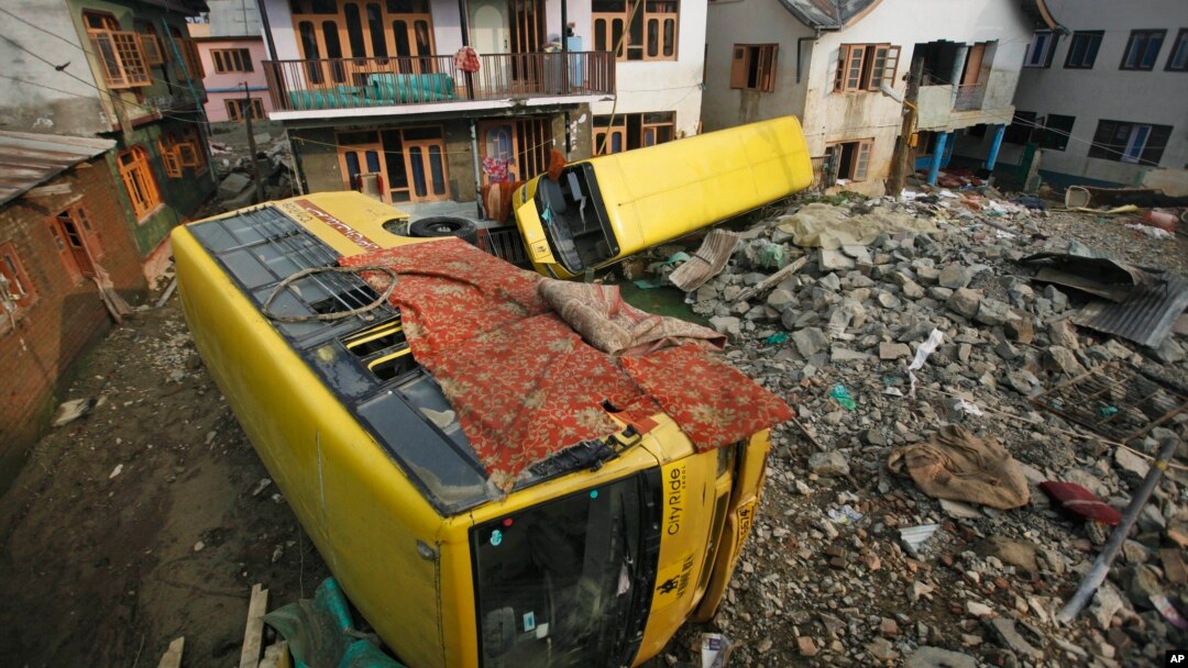 Bis sekolah yang terseret arus saat banjir bandang empat minggu yang lalu, terlihat masih teronggok di area permukiman penduduk di wilayah Srinagar, India (1/10). 