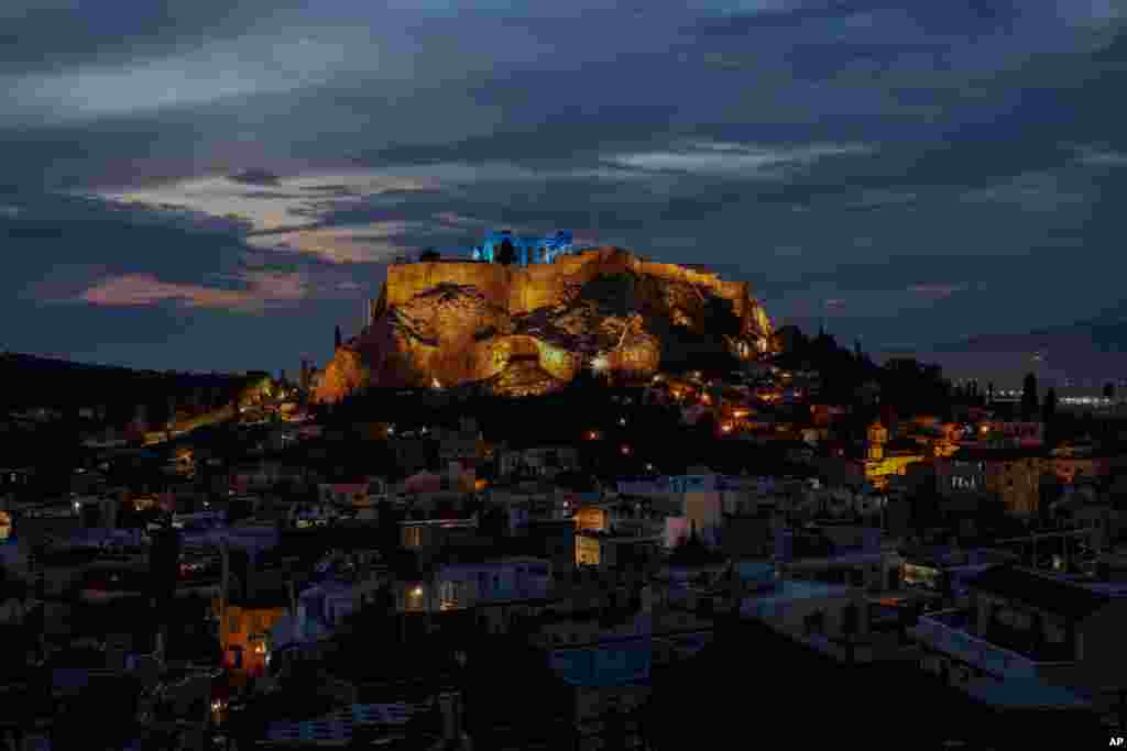 The ancient Parthenon temple atop the Acropolis hill is lit up in blue, in Athens, Greece.