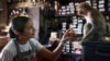 Supaporn Reanprayoorn, 38, a shopkeeper at Chayovanich, feeds her favorite long-tailed macaque, known as 'Sweet,' inside her shop, 