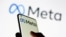 FILE - Woman holds smartphone with Meta logo in front of a displayed Facebook's new rebrand logo Meta in this illustration picture