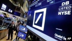 Traders walk by the post where Deutsche Bank is traded on the floor of the New York Stock Exchange, Monday, Sept. 26, 2016.