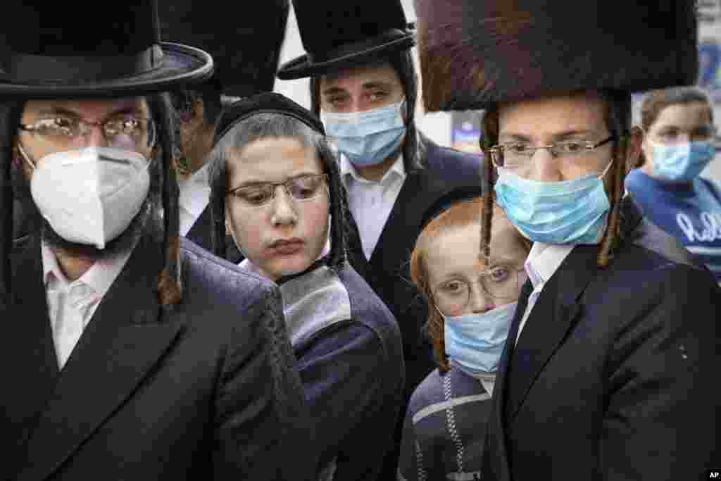 Members of Jewish Orthodox community gather around a journalist as he carries out an interview on a street corner, October 7, 2020, in the Borough Park neighborhood of the Brooklyn area of New York.