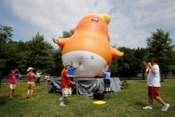 Protesters move a Baby Trump balloon into position before Independence Day celebrations, July 4, 2019, on the National Mall in Washington.