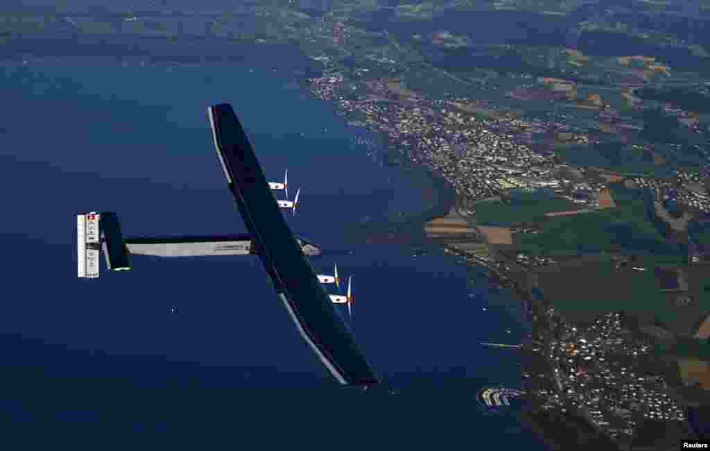 German test pilot Markus Scherdel steers the solar-powered Solar Impulse 2 aircraft over Lake Murten during a training flight at its base in Payerne, Switzerland, Sept. 27, 2014. 