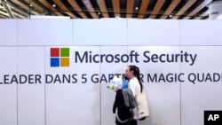 FILE - A woman walks in front of the Microsoft stand during the Cybersecurity Conference in Lille, northern France, Wednesday Jan. 29, 2020. Microsoft announced legal action Monday, Oct. 12, 2020 seeking to disrupt a major cybercrime digital network…