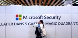 FILE - A woman walks in front of the Microsoft stand during the Cybersecurity Conference in Lille, northern France, Jan. 29, 2020.