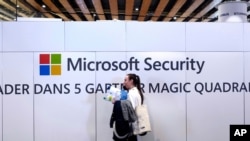 Seorang perempuan berjalan di depan logo Microsoft di Konferensi Keamanan Siber di Lille, utara Perancis, 29 Januari 2020. 