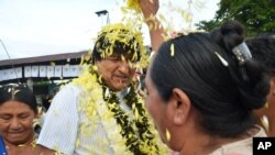 A coca farmer welcomes Bolivia's President Evo Morales, center, as he arrives to a polling station to vote in Villa 14 de Septiembre, in the Chapare region, Feb. 21, 2016.