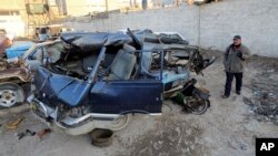 An Iraqi man inspects damaged vehicles in a car bomb attack in Baghdad, Iraq, Dec. 16, 2013. 