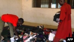 A student aided by a porter rummages through personal effects abandoned by students at the Federal College of Education in the northern Nigerian city of Kano, Sept. 17, 2014, following an attack by gunmen who stormed the lecture hall opening fire on students.