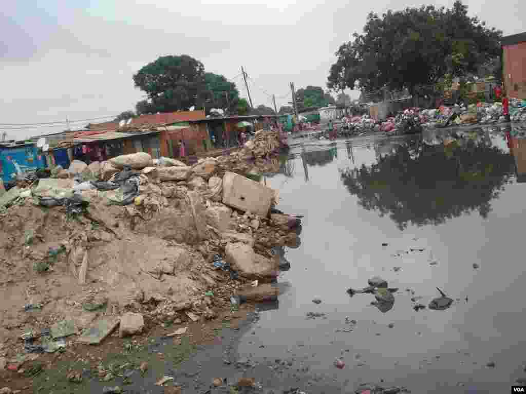 Angola, Luanda. Moradores tentam chegar ao seu destino, evitando a lama e o lixo. A chuva trouxe águas paradas e muito lixo, origem de epidemias. 25 de Abril 2014 