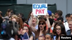 FILE - Females chant for equal pay for women as they wait for the United States women's national soccer team in New York City, July 10, 2019. 