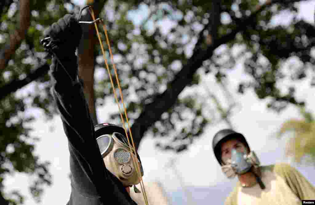 An opposition supporter uses a slingshot while clashing with security forces during a rally against the government of Venezuela's President Nicolas Maduro and to commemorate May Day in Caracas, May 1, 2019.