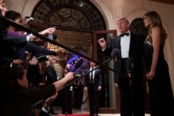 FILE - First lady Melania Trump listens as President Donald Trump speaks to reporters before his New Year's Eve party at his Mar-a-Lago property, Dec. 31, 2019, in Palm Beach, Fla.