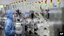 ARCHIVO - Empleados que usan equipo de protección trabajan en una planta de producción de semiconductores de Renesas Electronics en Beijing, China, el 14 de mayo de 2020.