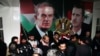 FILE - Freed Syrian detainees gather in front of posters showing Syrian President Bashar Assad, right, and his father Hafez Assad after they were released from Adra Prison, Jan. 15, 2013. A former Syrian military official who oversaw the prison has been arrested in Los Angeles.