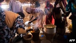 Women use fuel-efficient cook stoves make their meals in a food distribution center in the Rwanda camp for internally displaced people (IDP) in Tawila, North Darfur, March 4, 2014.