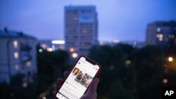 A user holds a smartphone with an opened Facebook page in Moscow, Russia, Thursday, June 10, 2021. Russian authorities have ordered Facebook and messaging app Telegram to pay steep fines for failing to remove banned content. The move could be part…