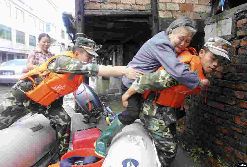 Polisi paramiliter menggendong seorang perempuan tua dari perahu karet dalam upaya penyelamatan warga-warga yang terjebak Topan Fitow di Taizhou, provinsi Zhejiang, China (8/10).