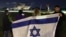 Israelis wave their national flag as a helicopter transporting newly released hostages, held by Hamas, Tel Aviv district on Nov. 28, 2023.