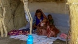 (FILES) A picture taken on March 20, 2024, shows a displaced woman and her children sitting in the shade of a straw hut at a camp in southern Gedaref state for people who fled Khartoum and Jazira states in war-torn Sudan.