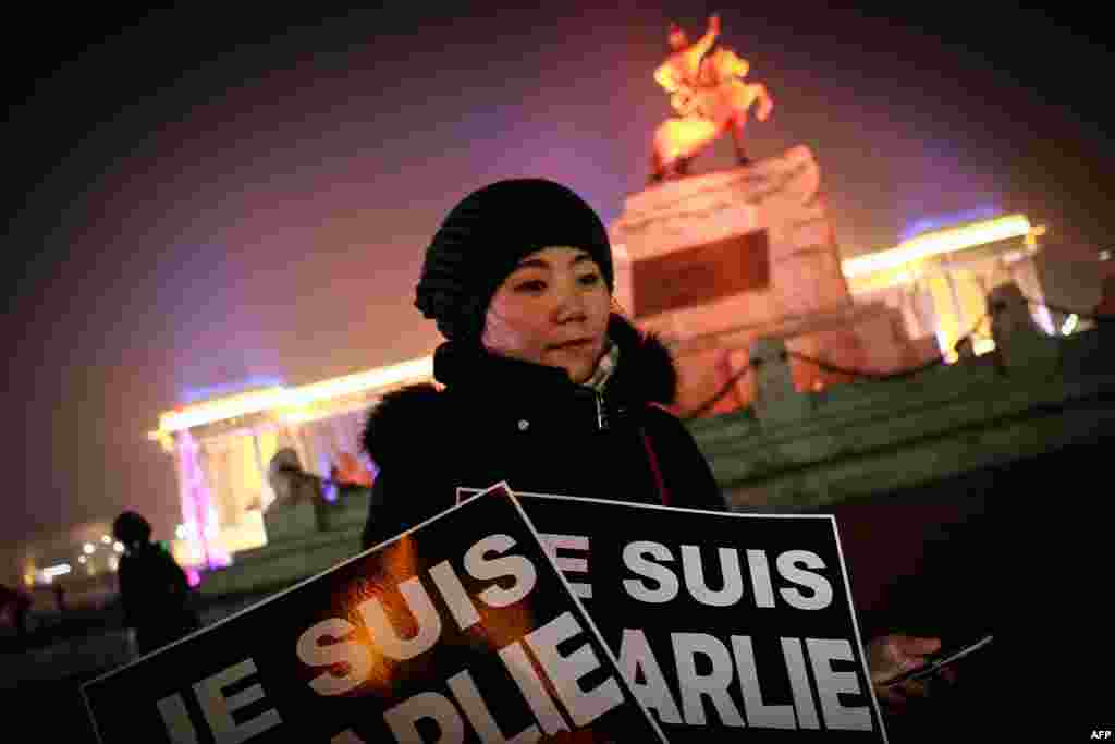 A Mongolian journalist holds placards reading "Je Suis Charlie" (I am Charlie) as she takes part in a candlelight vigil with members of the French community and other Mongolian journalists at Chinggis Square in Ulan Bator, Jan. 9, 2015. 