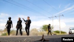 FILE - A tire-puncture device is seen as policemen patrol an area affected by blockades set by members of Santa Rosa de Lima Cartel to repel security forces during a police operation on the outskirts of Celaya, in Guanajuato state, Mexico, March 10, 2020.