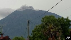 Gunung Agung mengeluarkan asap dan abu vulkanik dari kawahnya, terlihat dari Tulamben, Bali, Indonesia, 21 November 2017. (AP Photo/Wayan Wijaya)