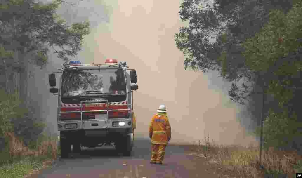 A firefighter watches as smoke covers a road in Bilpin, west of Sydney, Oct. 22, 2013. 