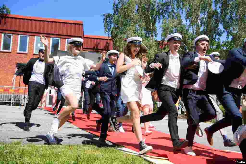 Students run out of their school celebrating their high school graduation at Nacka Gymnasium in Stockholm, Sweden.