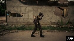 Un membre des forces armées congolaises passe devant un bâtiment incendié dans la ville de Yumbi, en République démocratique du Congo, le 1er février 2019. 