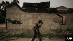 FILE: DRC FARDC soldier walks past a destroyed home in Yumbi, Maï-Ndombe. Taken Feb. 1, 2019.