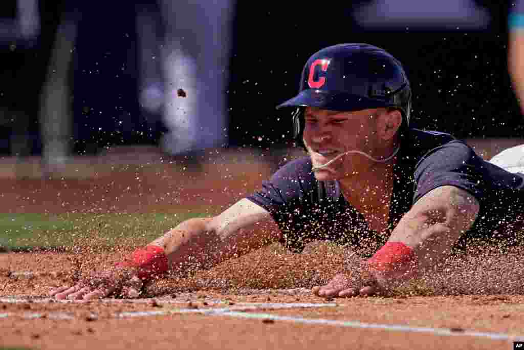 Cleveland Indians Jake Bauers slides home to score on a double by Josh Naylor during the first inning of a spring training baseball game against the Seattle Mariners, March 2, 2021, in Peoria, Arizona.