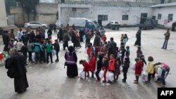 FILE - Children of Syrian families displaced from the Maaret Al-Numan region gather in the yard of a former jail turned into a makeshift refugee shelter in the northwestern city of Idlib, Dec. 31, 2019.