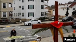 Seorang umat paroki mengambil daun palem di luar Gereja Katolik Sakramen Suci pada perayaan Minggu Palma di tengah wabah COVID-19 di Worcester, Massachusetts, 5 April 2020. (Foto: Reuters)