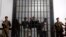 Yemeni soldiers stand guard as suspected al-Qaida militants, behind bars, attend a court hearing in Sanaa, Yemen, March, 4, 2013. 