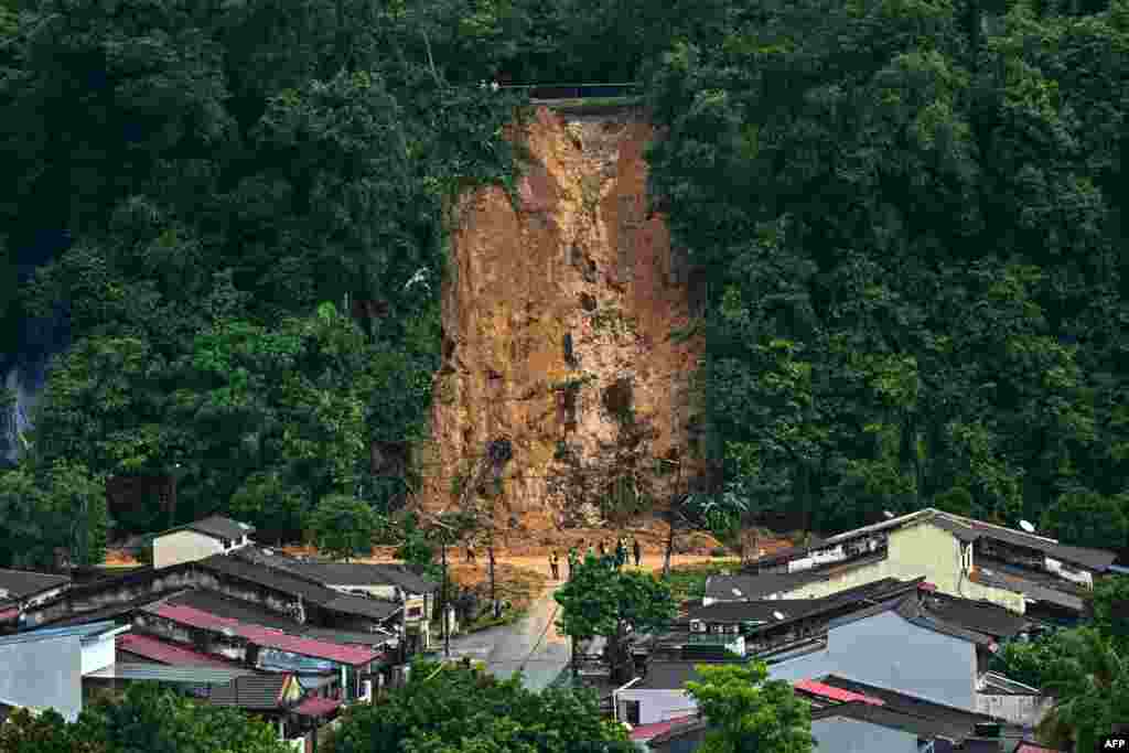 Malaysian officials inspect the site of a landslide following heavy rains in a residential area at Taman Melawati in Kuala Lumpur as authorities told residents of nearby homes to evacuate.(Photo by Mohd RASFAN / AFP)