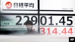A man stands in front of an electronic stock board showing Japan's Nikkei 225 index at a securities firm as a car passes by in Tokyo, July 15, 2020. 