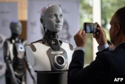 A visitor takes a picture of humanoid AI robot "Ameca" at the booth of Engineered Arts company during the world's largest gathering of humanoid AI Robots as part of International Telecommunication Union (ITU) AI for Good Global Summit in Geneva, on July 5