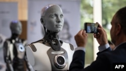 Posetilac slika humanoidnog robota Amiku na samitu o pozitivnoj upotrebi veštačke inteligencije u Ženevi, 6. jula 2023. (Foto: AFP/Fabrice Coffrini)