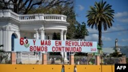 People walk past a banner hung to honor the Jan. 1, 2019, celebration of the 60th anniversary of the Cuban revolution in Santiago de Cuba, Cuba, Dec. 31, 2018.