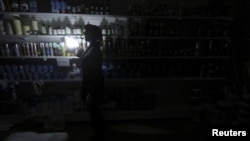 An employee works at an appliance shop lit with candles Nov. 22, 2015, due to a power cut in Simferopol, Crimea.