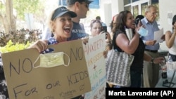 Joann Marcus of Fort Lauderdale, left, cheers as she listens to the Broward School Board's emergency meeting, Wednesday, July 28, 2021, in Fort Lauderdale, Fla. (AP Photo/Marta Lavandier)