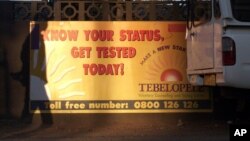 FILE - The shadow of a pedestrian is cast over a banner for a HIV testing center in Gaborone, Botswana.